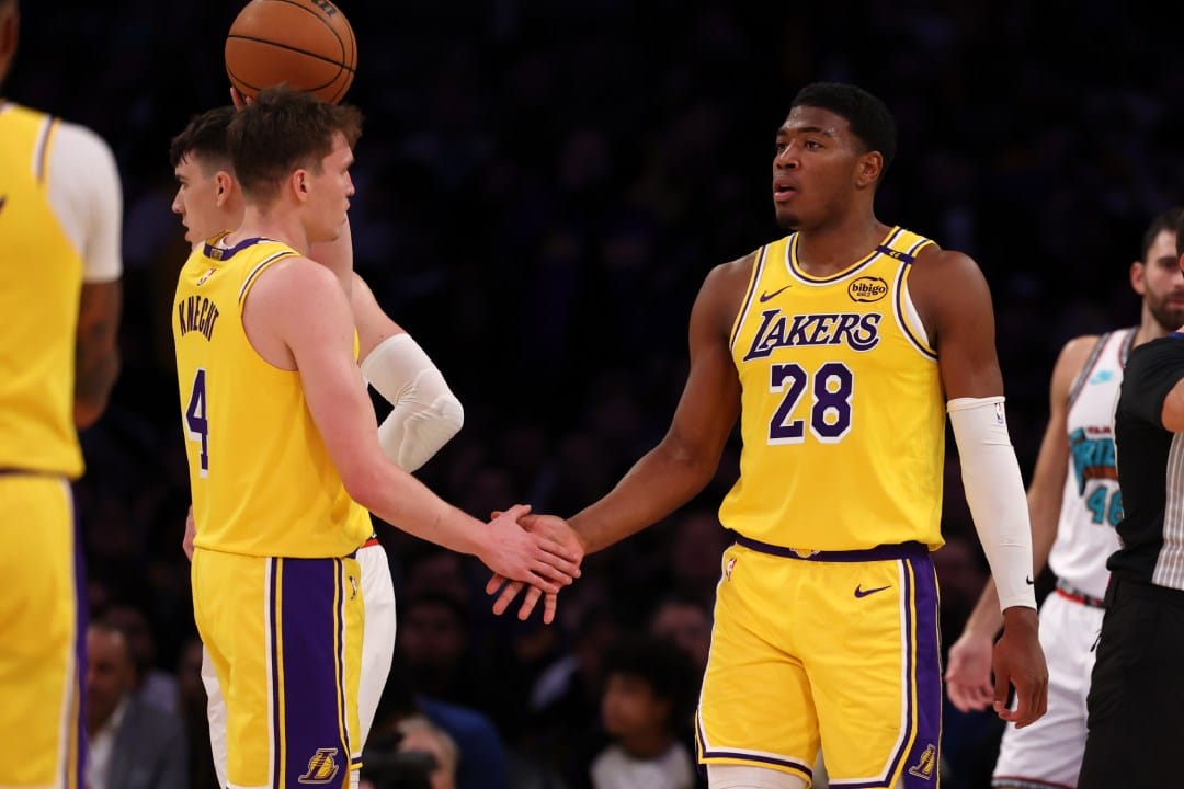 Rui Hachimura y Dalton Knecht chocan manos durante un encuentro.
