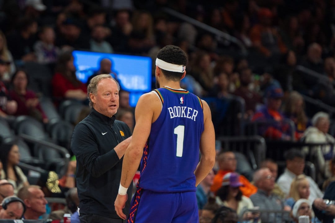 Budenholzer, Booker conversan durante un partido.