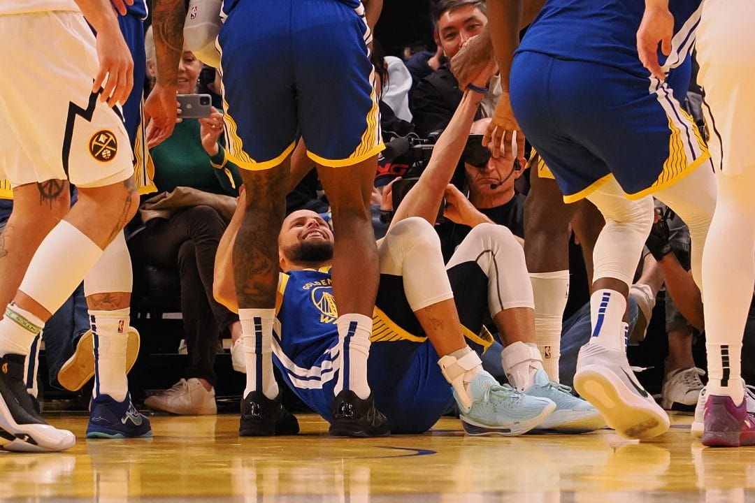 Stephen Curry es ayudado a levantarse por sus compañeros.