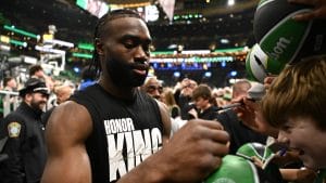 Jaylen Brown firma balones a pie de grada.
