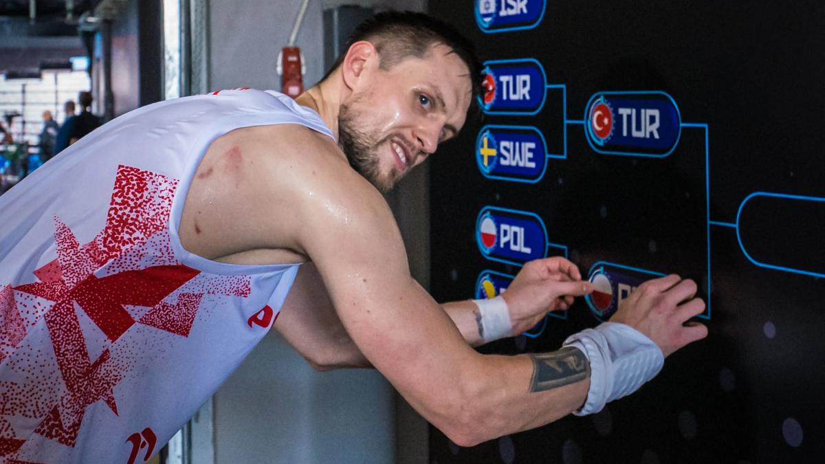 Jugador de la selección de Polonia coloca el nombre de su país en el cuadro del torneo.