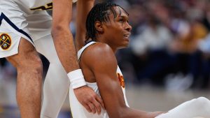 Jamal Murray socorre a Peyton Watson para tratar de levantarlo.