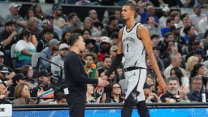 Victor Wembanyama, saludando a su entrenador Mitch Johnson, durante un partido de los Spurs.