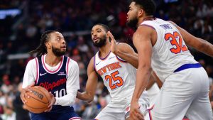 Darius Garland trata de anotar ante la presencia de Mikal Bridges y Karl-Anthony Towns.